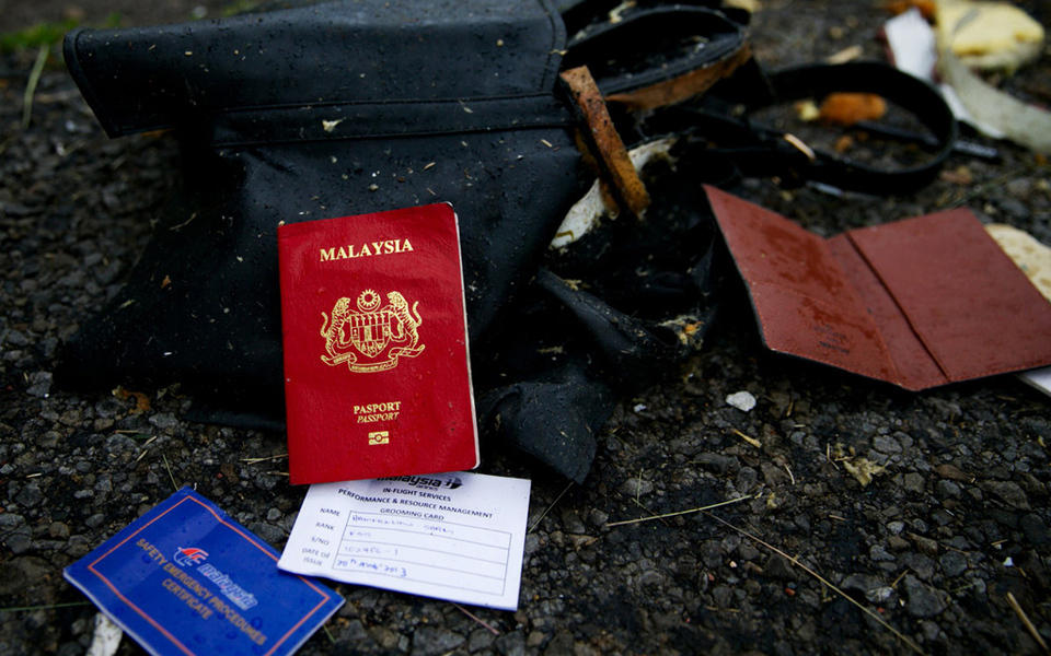 图为一本马来西亚护照，一个皮夹以及旅客登记表
